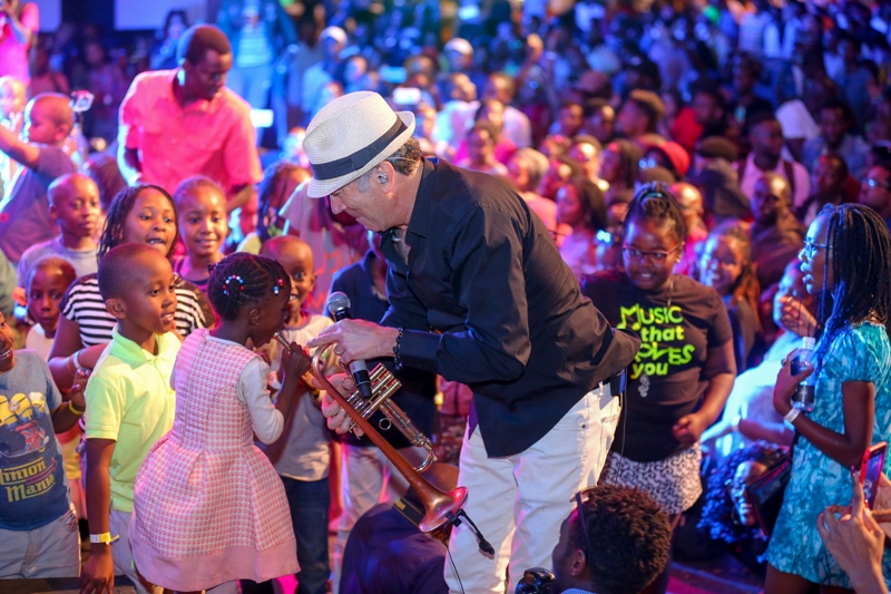 US based jazz star Ricky Braun enjoys blowing saxophone with a young jazz fan during the Safaricom International jazz festival.
